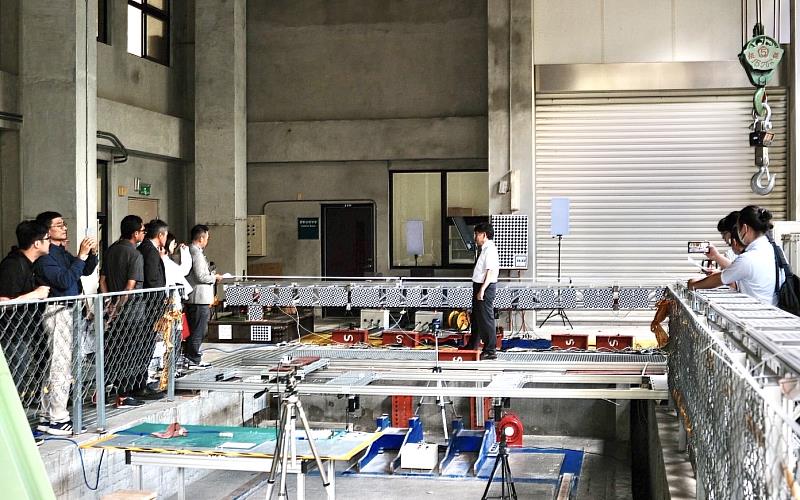 計畫總主持人、暨大土木系終身特聘教授施明祥博士（中），於暨大震害實驗室親自介紹NEMELIFT智慧輕便橋研究成果，並現場示範中性平衡機構（NEM）及主動控制系統，帶領與會貴賓了解智慧橋梁技術從理論研究到實體應用的實踐成效。