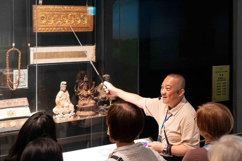 藏傳佛教研究者葉靈毅在世界宗教展示大廳導覽佛教展櫃。(圖由世界宗教博物館提供)
