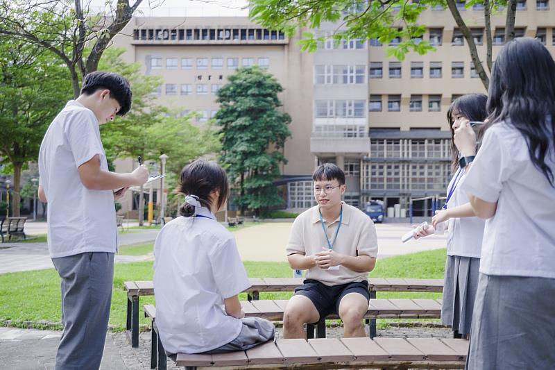 麗山高中學生在校園中以小組方式圍繞境外生進行訪談,學習用英文傾聽與提問。
