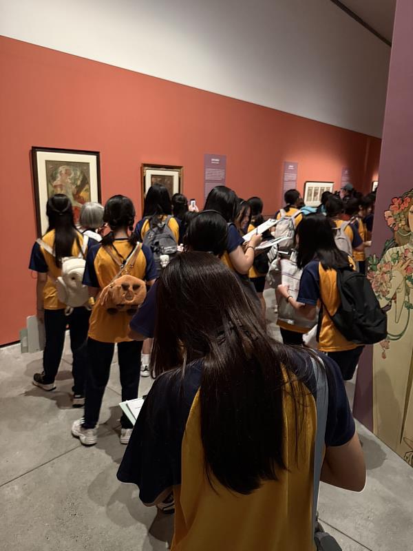 學生在慕夏作品前邊聽導覽,邊觀察畫作的線條、配色與構圖。/旗山國中拍攝提供