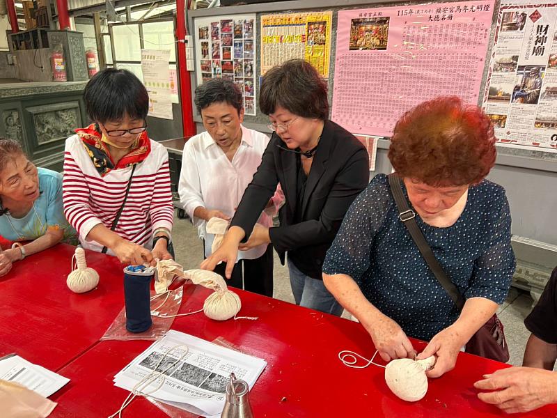 詹凱毓老師協助居民製作艾草草藥捶,現場示範草藥材料的包覆方式。(照片/校方提供)
