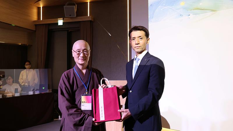 生命和平大學督導顯月法師(左)致贈結緣品給日本長崎縣平戶市文化交流課課長松尾桂宏。(圖片提供/靈鷲山佛教教團)