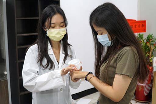 大葉大學藥保系碩士生林慧霞(左)幫受試者擦凝膠