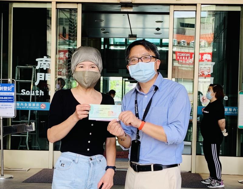 新北市南風慈善關懷協會理事長許淑峰（左）響應防疫基金  捐100萬善款要幫助弱勢家庭  她特地將自己臉部包得密不透風  親自開車到市府將支票交給社會局專委黃逢明。