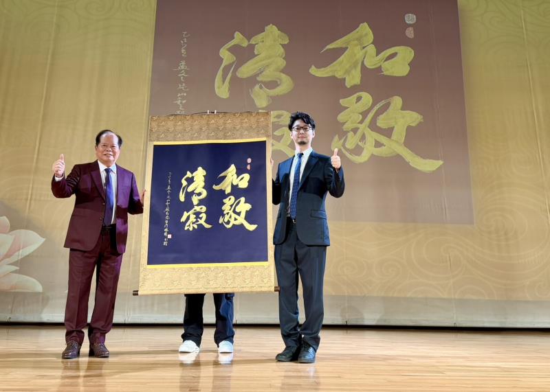 右一為日台交流協會新聞文化部長荒木直哉，左為林暉博士，雙方於典禮中共同展示林博士親題書法作品〈和敬清寂〉，象徵日台文化交流的誠意與友誼。