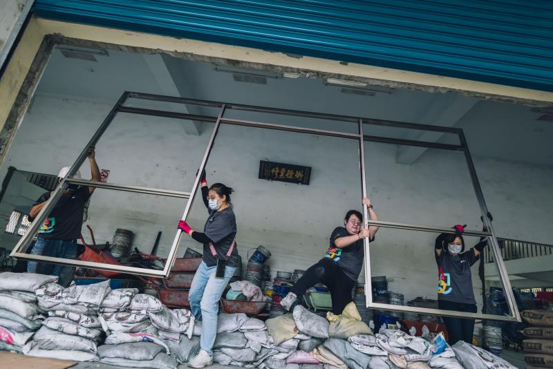 志工們組裝好的鋁門框架起來，後續將鎖緊在牆面上，以便後續安裝新大門.