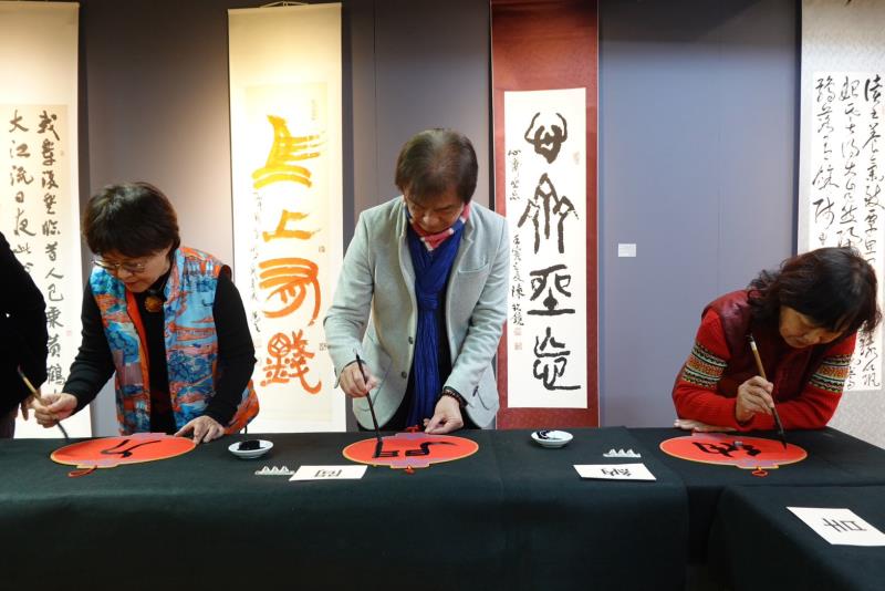 華梵大學人文與藝術學院黃智陽院長（中）與其他書法家現場揮毫寫春聯。