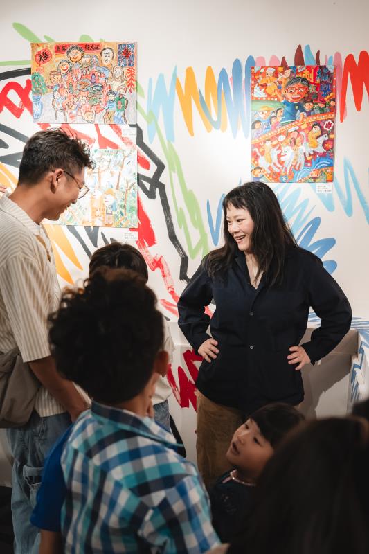 策展人李竹婷（右立者）以三歲女兒的日常塗鴉為靈感，於 B3 美術館牆面打造不規則筆畫軌跡，營造如同創作現場般的沉浸式空間。