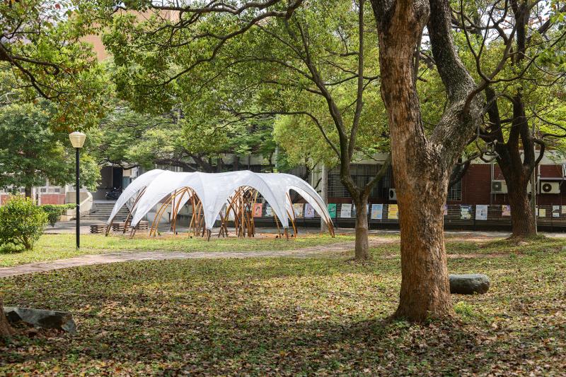 竹穹林 Bamboo Dome｜數位設計與竹構工法的結合
由日本結構技師萩生田秀之與台灣結構技師陳冠帆共同設計創作，作品以「竹拱圈」為核心概念。「拱」是最純粹的結構形式，也是最能展現竹材柔韌特性的幾何語言。設計團隊特別選擇設置於工程館旁，希望透過竹材這種自然材料，讓工程與建築相關科系學生重新思考結構設計的可能性。
從空中俯瞰，《竹穹林》猶如透過放射狀排列形成宛如星芒般展開的空間構造，走入其中，則能感受到層層竹拱所形成的半開放空間。更重要的是，《竹穹林》展現了台灣竹構發展的重要轉變。從早期偏向工藝與裝置藝術的表現形式，逐步邁向結構計算、數位設計與國際合作的建築實踐。
